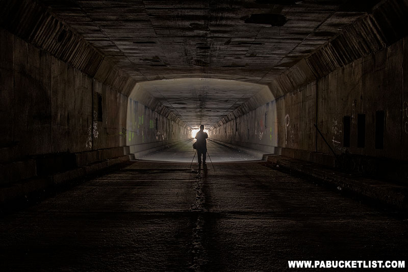 A photographer illuminated by a spotlight inside the Sideling Hill Tunnel.