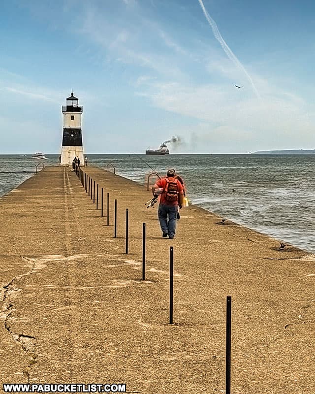Fishermen walking towards the North Pier Lighthouse at Presque Isle State Park in Erie.