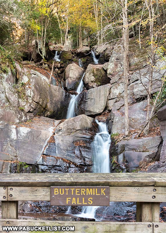 Buttermilk Falls sign on rail trail bridge below falls.
