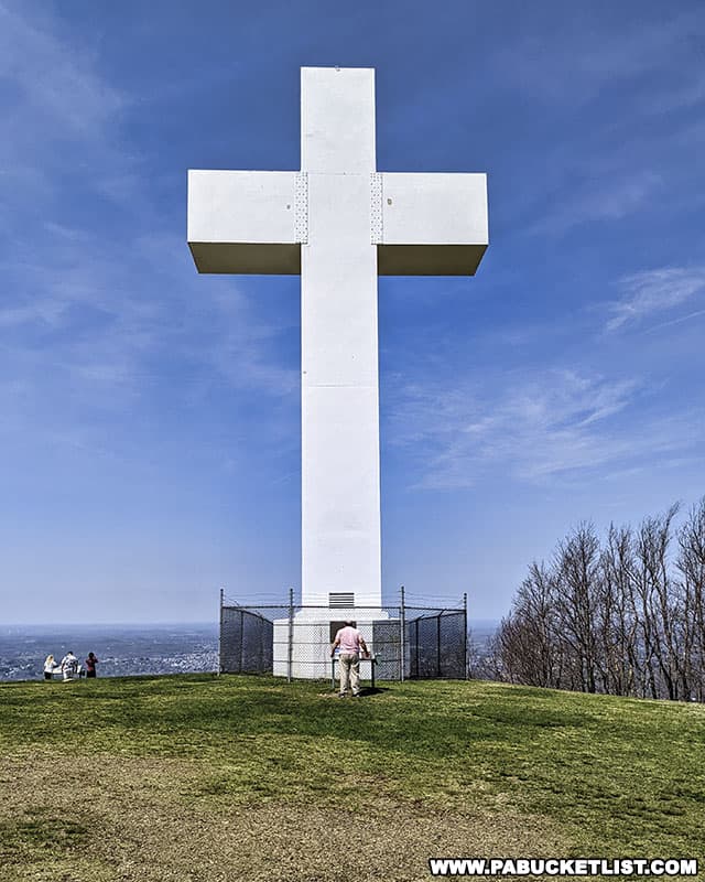 A man standing next to the Jumonville Cross gives a sense of scale to the 60 foot-tall structure.