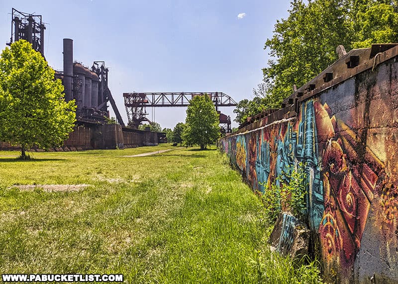 A long wall at the rear of the Carrie Blast Furnaces property decorated by muralists from around the world.