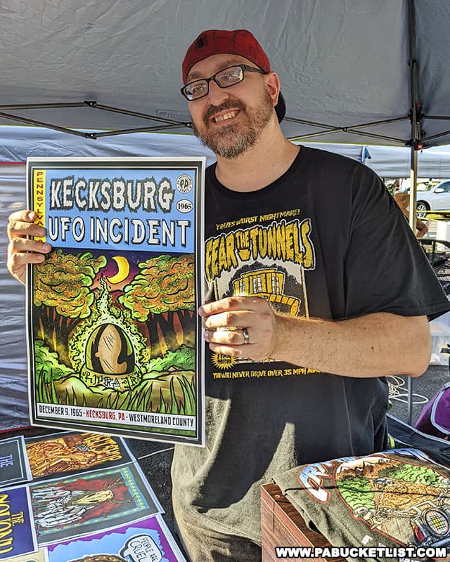 Joe from Crytoteeology.com displaying one of his original art prints for sale at the Kecksburg UFO Festival.