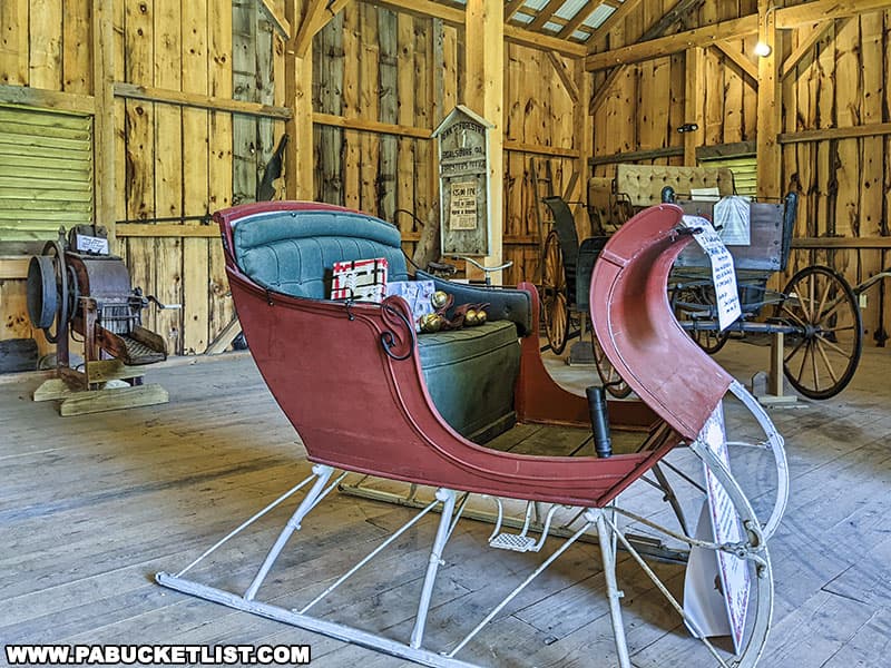 Horse-drawn carriages and a sleigh on display inside the bank barn at the Boalsburg Heritage Museum.