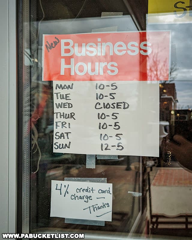 The business hours for the High Street Emporium Antique Store in Ebensburg Pennsylvania are posted in the door on this sign.