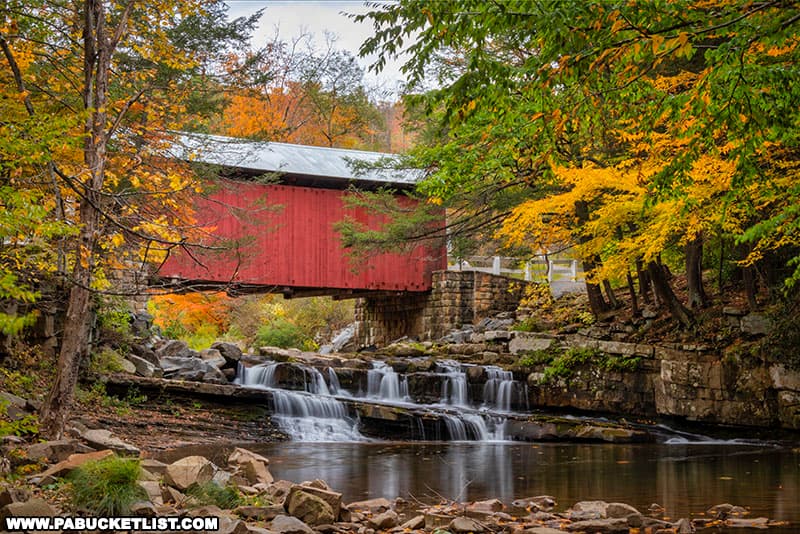 Fall foliage around the waterfall beneath the Pack Saddle Bridge over Brush Creek in Somerset County Pennsylvania.