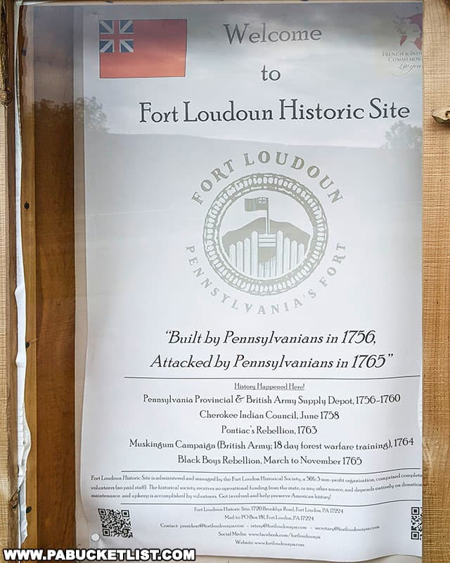 Informational poster at Fort Loudoun Historic Site, Pennsylvania, displaying a Union Jack flag and the fort's logo with text: 'Welcome to Fort Loudoun Historic Site.' Below it reads: 'Built by Pennsylvanians in 1756, Attacked by Pennsylvanians in 1765' with a list of historical events associated with the fort, including 'Cherokee Indian Council, June 1758' and 'Pontiac's Rebellion, 1763.'