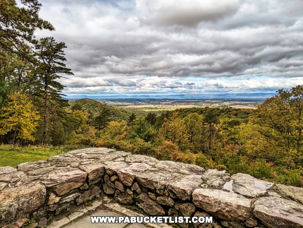 View from the stone terrace wall at Cameron-Masland Mansion overlooking the forested South Mountain and distant Cumberland Valley under cloudy skies.