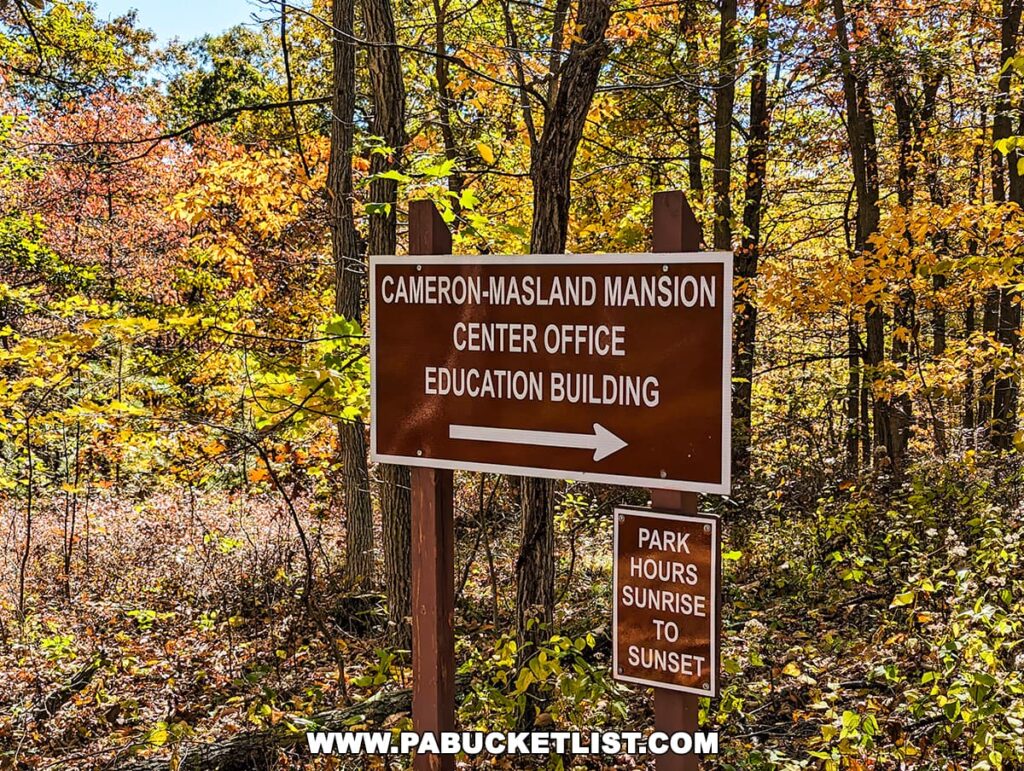 Directional sign for Cameron-Masland Mansion Center Office and Education Building with park hours, amidst vibrant fall foliage.