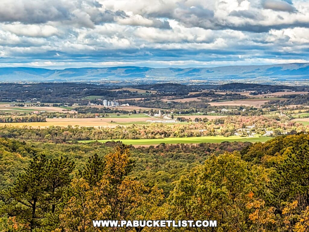 Expansive view over Cumberland Valley from Cameron-Masland Mansion, showcasing rolling farmlands and distant mountains under a cloudy sky.