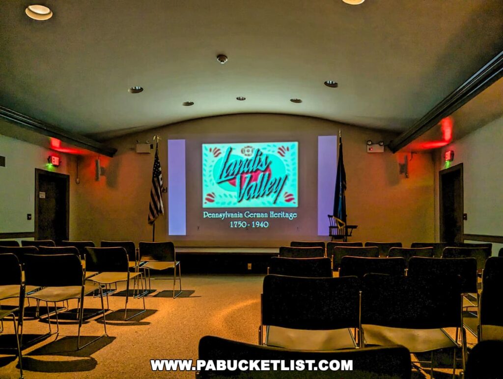 Auditorium inside the Landis Valley Museum in Lancaster County, Pennsylvania, with rows of chairs facing a large screen displaying the title 'Landis Valley Pennsylvania German Heritage 1750-1940.'