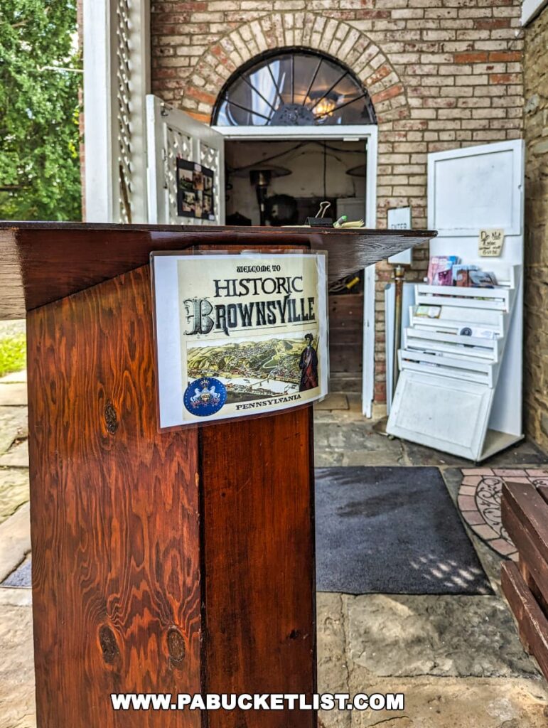 Entrance podium with a sign titled "Historic Brownsville Pennsylvania" at Nemacolin Castle, featuring a view into the brick entryway of the castle, featuring a semi-circular transom window.