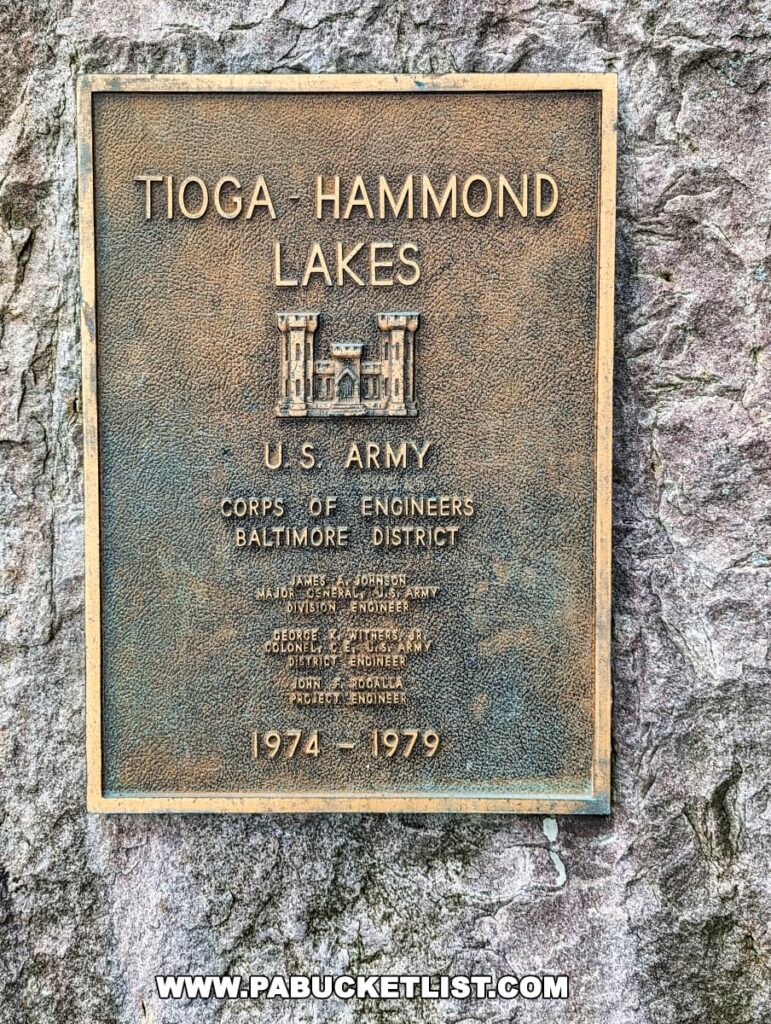 A bronze plaque mounted on a stone at the Tioga-Hammond Lakes Overlook in Tioga County, Pennsylvania, commemorating the creation of the Tioga-Hammond Lakes by the U.S. Army Corps of Engineers, Baltimore District, between 1974 and 1979, with names of key personnel involved in the project.