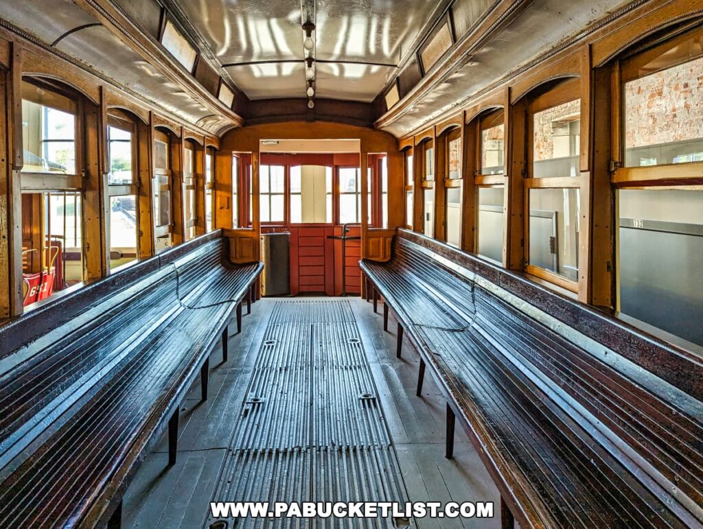 Interior of a vintage trolley car with wooden benches and flooring, displayed at the Electric City Trolley Museum in Scranton, Pennsylvania, illuminated by natural light from the windows.