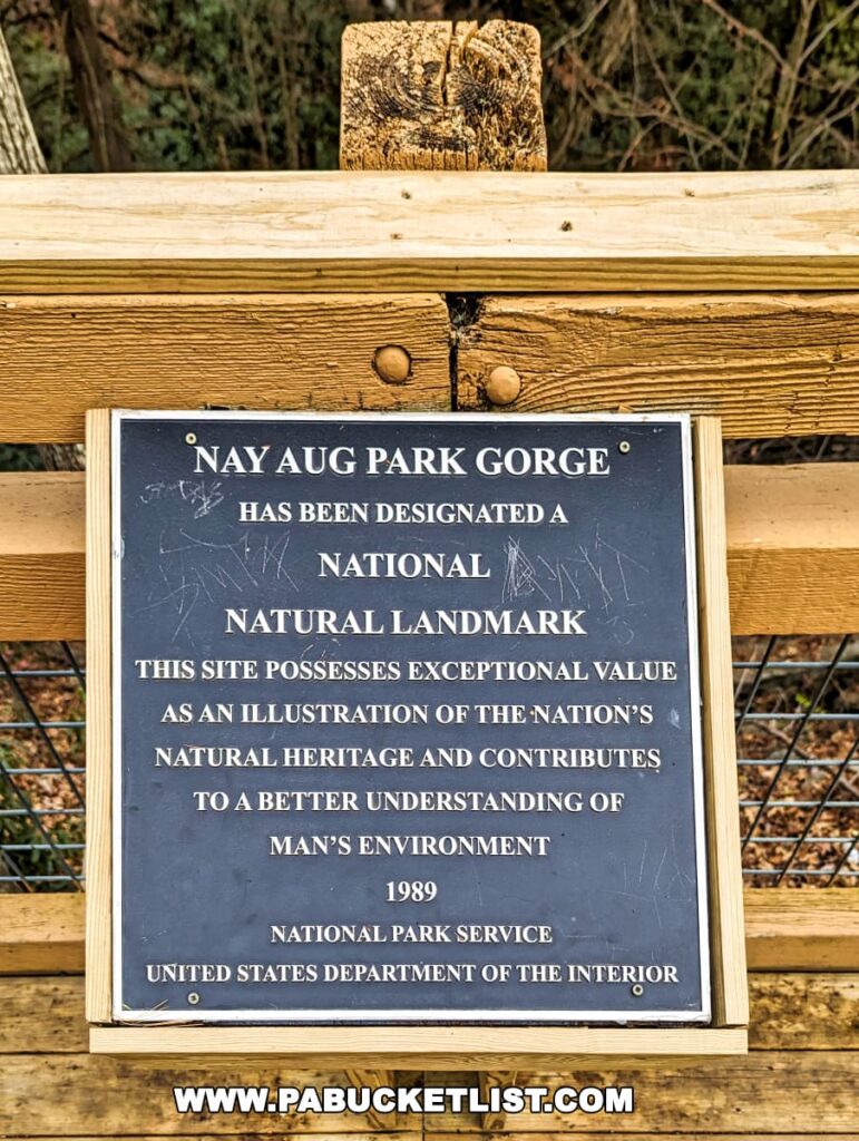 An informational plaque at Nay Aug Park in Scranton, Pennsylvania, mounted on a wooden fence, proclaiming the Nay Aug Park Gorge as a National Natural Landmark. The plaque, issued by the National Park Service, United States Department of the Interior, states that the site was designated in 1989 for its exceptional value in illustrating the nation's natural heritage.