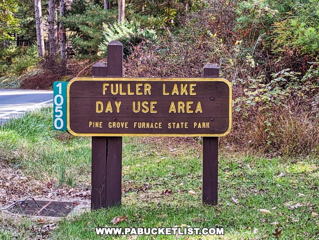 A wooden sign at Pine Grove Furnace State Park in Cumberland County, PA, indicating the "Fuller Lake Day Use Area." The sign has yellow lettering on a dark background and is mounted on a post with a green address marker reading "1050." The sign is set against a backdrop of forest undergrowth.