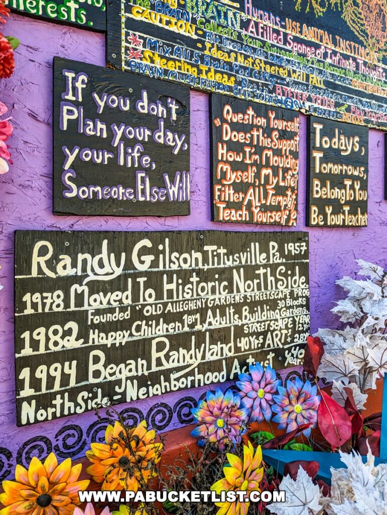 Colorful signs with inspirational quotes and the history of Randy Gilson at Randyland in Pittsburgh, adorned with vibrant painted flowers.