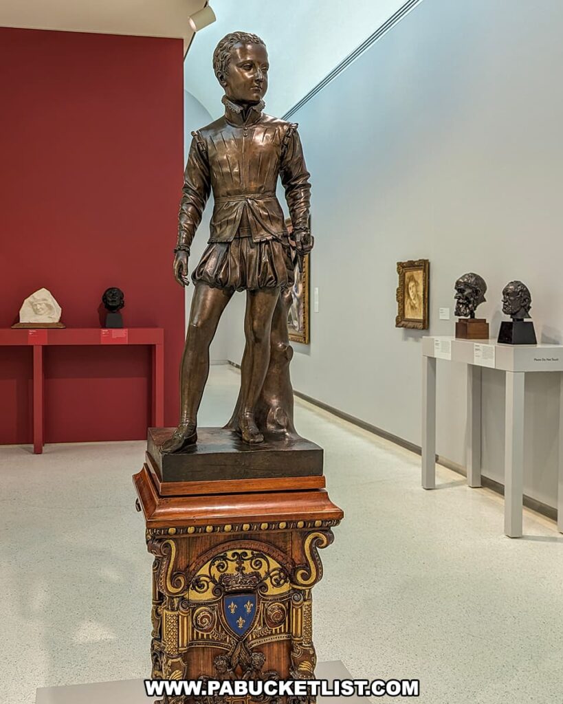 Bronze statue of a young Henry IV on an ornate pedestal, displayed in the gallery of the Carnegie Museums of Art and Natural History in Pittsburgh, surrounded by art and busts.