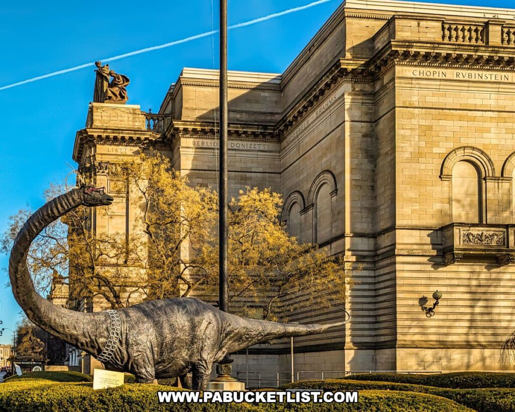 The exterior of the Carnegie Museums of Art and Natural History in Pittsburgh, PA, during golden hour. A striking sculpture of a dinosaur, possibly a Diplodocus, with a long neck reaching upwards, is positioned in front of the museum's grand stone facade. Names of notable figures like Chopin and Rubinstein are inscribed high on the building's exterior, beneath ornate cornices and beside classical columns. Contrails from airplanes cross the clear blue sky above, adding a contemporary contrast to the historical setting.