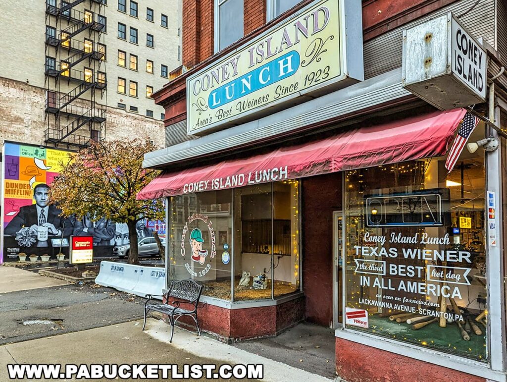 The colorful storefront of Coney Island Lunch in downtown Scranton, Pennsylvania, featuring a bright sign reading 'Coney Island Lunch, America's Best Wieners Since 1923.' Below the awning, a window decal advertises 'Coney Island Lunch Texas Wiener - The third BEST hot dog in ALL AMERICA.'