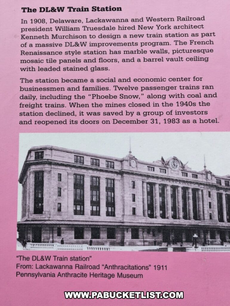 An informational sign about the DL&W Train Station at the Scranton Iron Furnaces Historic Site, set on a pink background. It details the station's history, constructed in 1908 by the Delaware, Lackawanna and Western Railroad with design by architect Kenneth Murchison. The sign describes the station's French Renaissance style with marble walls, mosaic tile panels and floors, and a barrel vault ceiling with leaded stained glass. It became a social and economic hub, operating twelve passenger trains daily until the mines' closure in the 1940s. It was later saved by investors and reopened as a hotel in 1983. The sign features a black and white photo of the station's facade, captioned "The DL&W Train station" from "Lackawanna Railroad 'Anthracitations'" 1911, Pennsylvania Anthracite Heritage Museum.