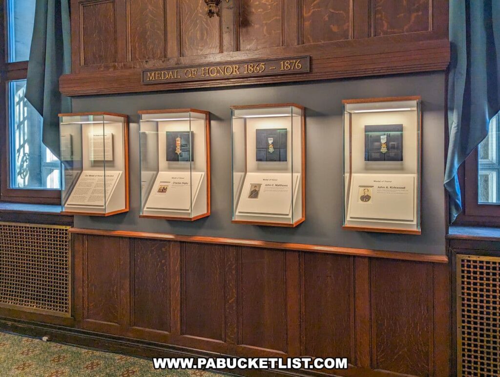 Wall display titled 'Medal of Honor 1865 - 1876' at the Soldiers and Sailors Memorial Hall and Museum in Pittsburgh, PA. It features framed Medals of Honor and accompanying descriptions of the recipients' heroic deeds. Each frame is mounted on a wooden panel beneath an inscribed header, honoring the valor and sacrifice of these distinguished individuals.