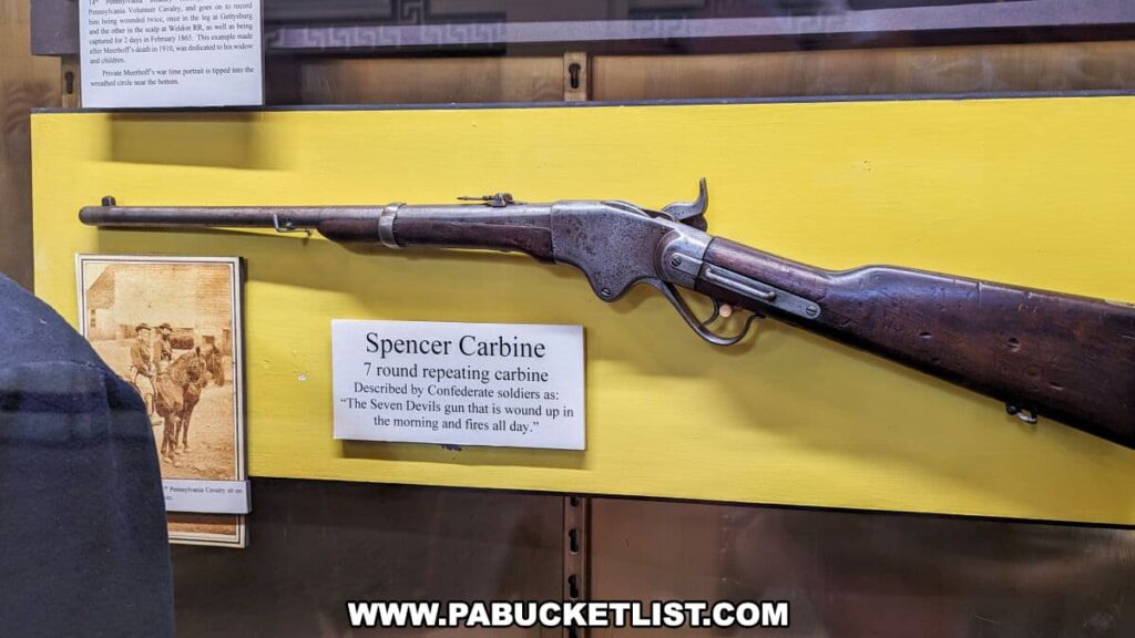 Historic Spencer Carbine rifle on display at the Soldiers and Sailors Memorial Hall and Museum in Pittsburgh, PA. The 7-round repeating carbine, mounted against a yellow background, is accompanied by an informational placard describing it as a significant weapon described by Confederate soldiers as 'The Seven Devils gun that is wound up in the morning and fires all day.' Below the gun is a vintage photograph, contributing to the artifact's historical context.