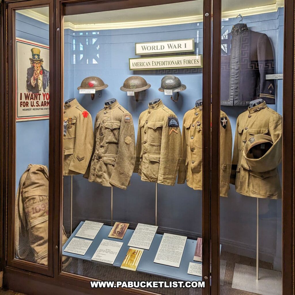 World War I exhibit at the Soldiers and Sailors Memorial Hall and Museum in Pittsburgh, PA, featuring American Expeditionary Forces uniforms. Displayed are several service jackets with insignia, helmets, and military gear, accompanied by informative placards. A classic Uncle Sam 'I Want You' recruiting poster adds a touch of historical context to the collection.