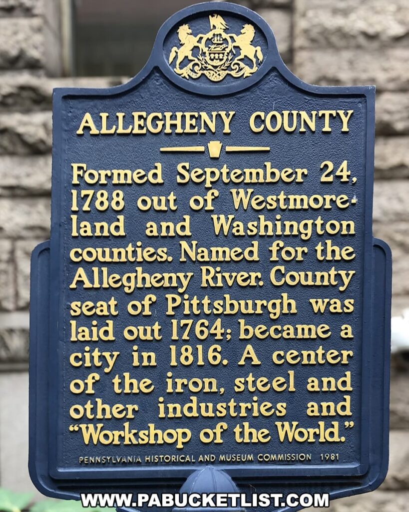 A historical marker plaque in Allegheny County, Pennsylvania, painted blue with raised gold lettering. At the top, a decorative arch contains the Pennsylvania state emblem with two horses and an eagle. The text details the county's formation on September 24, 1788, from parts of Westmoreland and Washington counties, and its naming after the Allegheny River. It mentions Pittsburgh as the county seat, laid out in 1764 and becoming a city in 1816, known for its iron, steel, and other industries, historically referred to as the "Workshop of the World." The bottom credits the Pennsylvania Historical and Museum Commission 1981. The plaque is against a background of stone masonry.