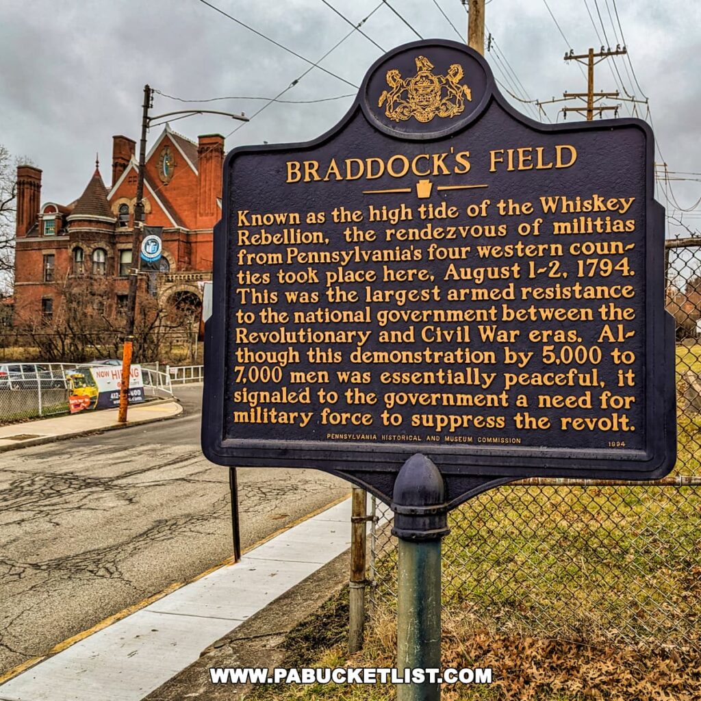 Historical marker for "Braddock's Field" detailing its significance as the site of the rendezvous of militias during the Whiskey Rebellion in August 1794, located at Braddock's Battlefield History Center near Pittsburgh. The sign, adorned with the Pennsylvania state emblem, explains that this was the largest armed resistance to the U.S. government between the Revolutionary and Civil War eras. In the background, there's a view of a gothic-style brick building with turrets, power lines, and a cloudy sky overhead.