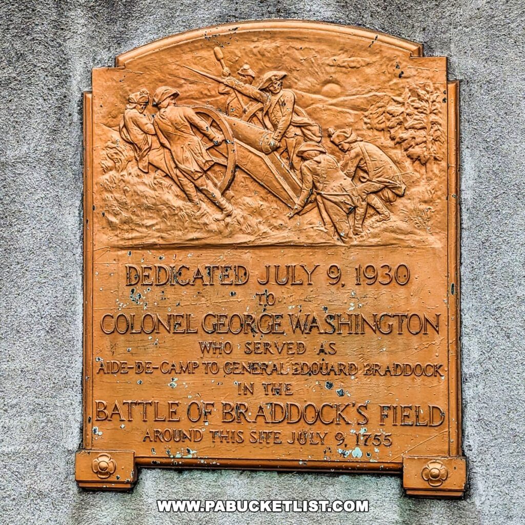 A close-up of a bronze historical plaque at Braddock's Battlefield History Center near Pittsburgh, dedicated to Colonel George Washington. The plaque, with raised lettering and a relief depicting a battle scene, commemorates Washington's service as Aide-de-Camp to General Edward Braddock at the Battle of Braddock's Field on July 9, 1755. The dedication date on the plaque is July 9, 1930.