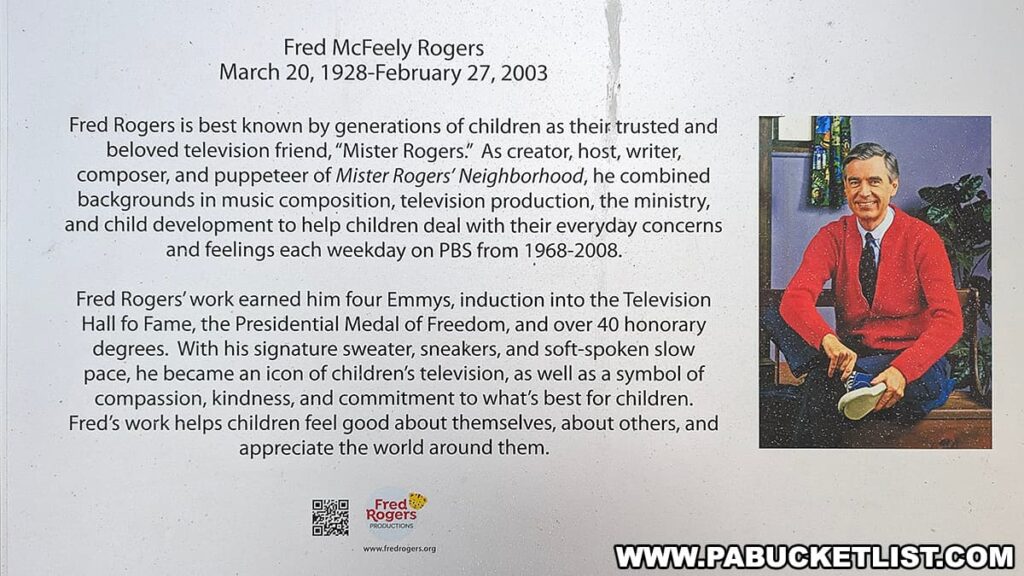 A plaque commemorating Fred McFeely Rogers, featuring his biography and contributions to children's television. It includes a photograph of Fred Rogers in a red sweater, changing into sneakers, set against a backdrop of his show's set. The text recounts his role as the creator, host, writer, composer, and puppeteer of "Mister Rogers' Neighborhood" from 1968-2008, noting his blend of music composition, television production, and ministry to address children's concerns. Rogers received four Emmys, was inducted into the Television Hall of Fame, awarded the Presidential Medal of Freedom, and received over 40 honorary degrees. His legacy is described as an icon of children's television symbolizing compassion, kindness, and commitment to children's well-being.