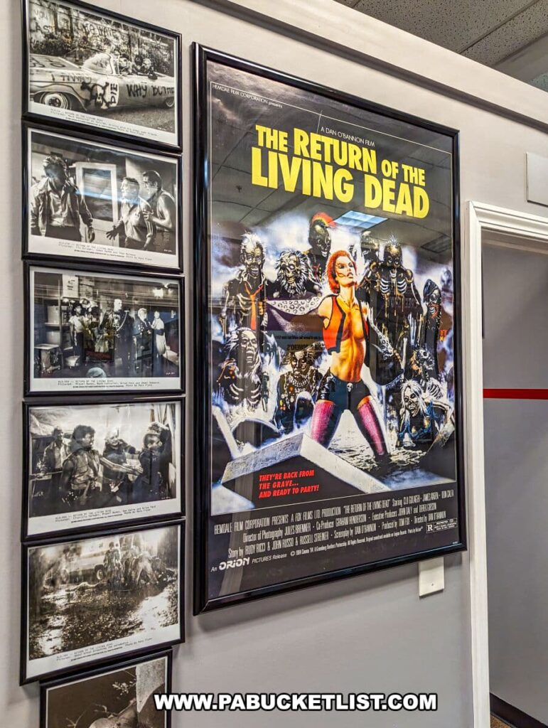 An exhibit at the Living Dead Museum featuring a vibrant poster of 'The Return of the Living Dead' surrounded by a series of black and white photographs depicting scenes from the movie. The poster stands out with its bold colors and a group of zombies, contrasting the monochrome stills that capture various moments of action and suspense from the film. This display celebrates the influence of the Living Dead series and its spin-offs, contributing to the museum's comprehensive homage to the zombie genre.