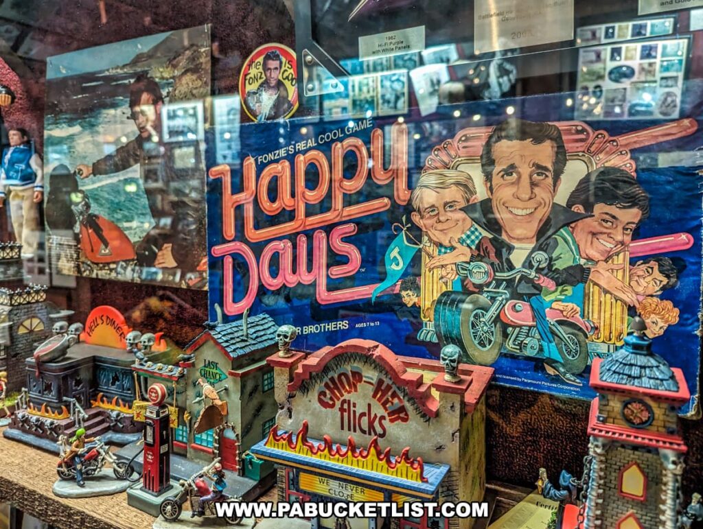 A display of memorabilia from the television show "Happy Days" at Bill's Old Bike Barn museum in Bloomsburg, Pennsylvania. The collection includes a colorful board game featuring illustrations of the cast, a Fonzie-themed pin, and various miniature dioramas and figurines, including one of Fonzie on his motorcycle. These items are showcased alongside other vintage items, capturing the nostalgia of the iconic 1970s American TV series.