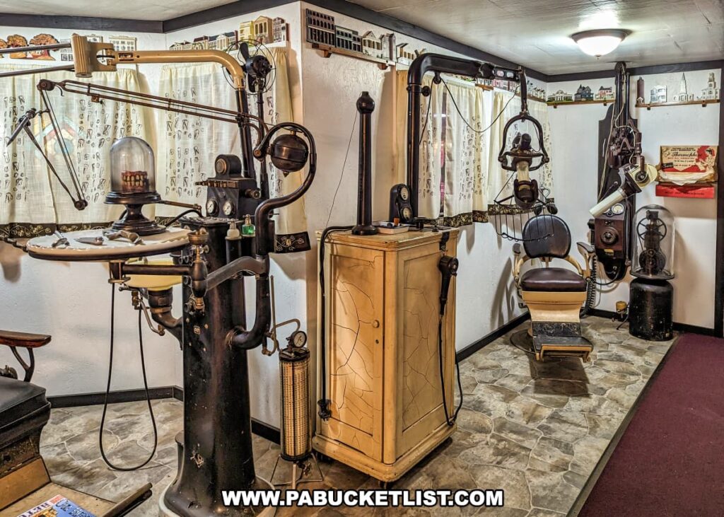 An exhibit at Bill's Old Bike Barn museum in Bloomsburg, Pennsylvania, displays vintage dental office equipment. The collection includes an early dental chair, an elaborate dental drill apparatus, and various other antique tools and devices used in dentistry. The setup is arranged to mimic a historical dental clinic, providing a glimpse into the evolution of dental care and equipment. Decorative elements like lace curtains with tooth illustrations and old-fashioned lamps complement the period look of this unique dental memorabilia display.