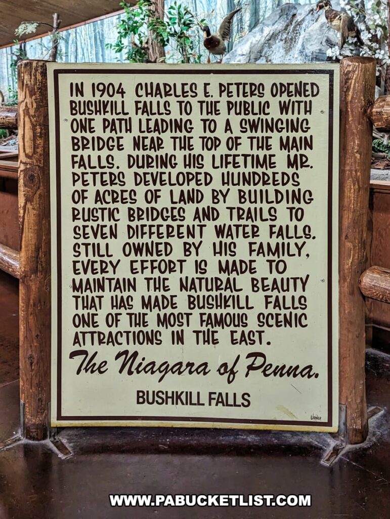 A historical information sign at Bushkill Falls in Pike County, Pennsylvania, details the origins of the park. According to the sign, Charles E. Peters opened Bushkill Falls to the public in 1904, offering access via a swinging bridge near the top of the main falls. The sign explains that throughout his life, Mr. Peters developed the land by constructing rustic bridges and trails that lead to seven different waterfalls. The text proudly states that the falls are still owned by the Peters family, and emphasizes the ongoing efforts to maintain the natural beauty that has made Bushkill Falls a renowned scenic attraction in the Eastern United States, often referred to as "The Niagara of Pennsylvania." The sign is framed by a wooden structure, evoking the park's natural setting and commitment to preserving its rustic charm.