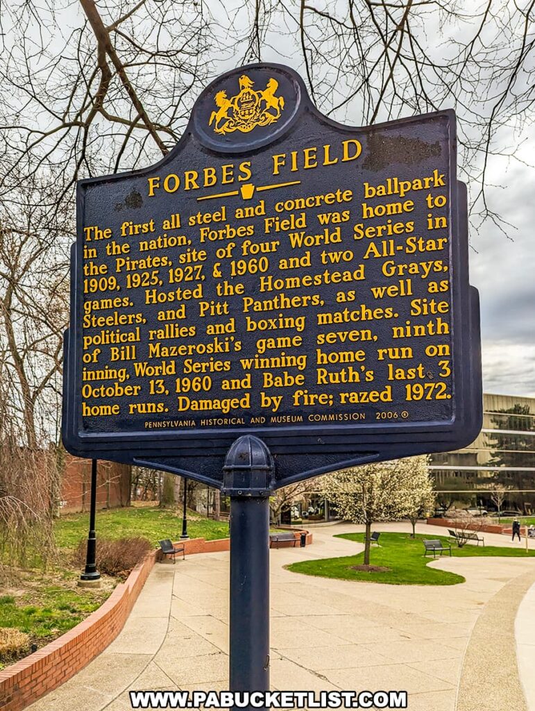 A historical marker stands in the foreground, detailing the significance of Forbes Field in Pittsburgh's Oakland neighborhood. Titled "FORBES FIELD," the marker commemorates the ballpark as the first all-steel and concrete structure of its kind in the nation, serving as the Pirates' home and hosting four World Series (1909, 1925, 1927, & 1960) and two All-Star games. It mentions the Homestead Grays, the Pitt Panthers, and various other events, including political rallies and boxing matches. Notably, it highlights Bill Mazeroski's game-winning home run in the 1960 World Series and Babe Ruth's last three home runs before the field was razed in 1972 due to fire damage. Set against a backdrop of bare trees and a brick-lined walkway leading to a modern building, the scene merges past sports glory with the present-day campus environment.