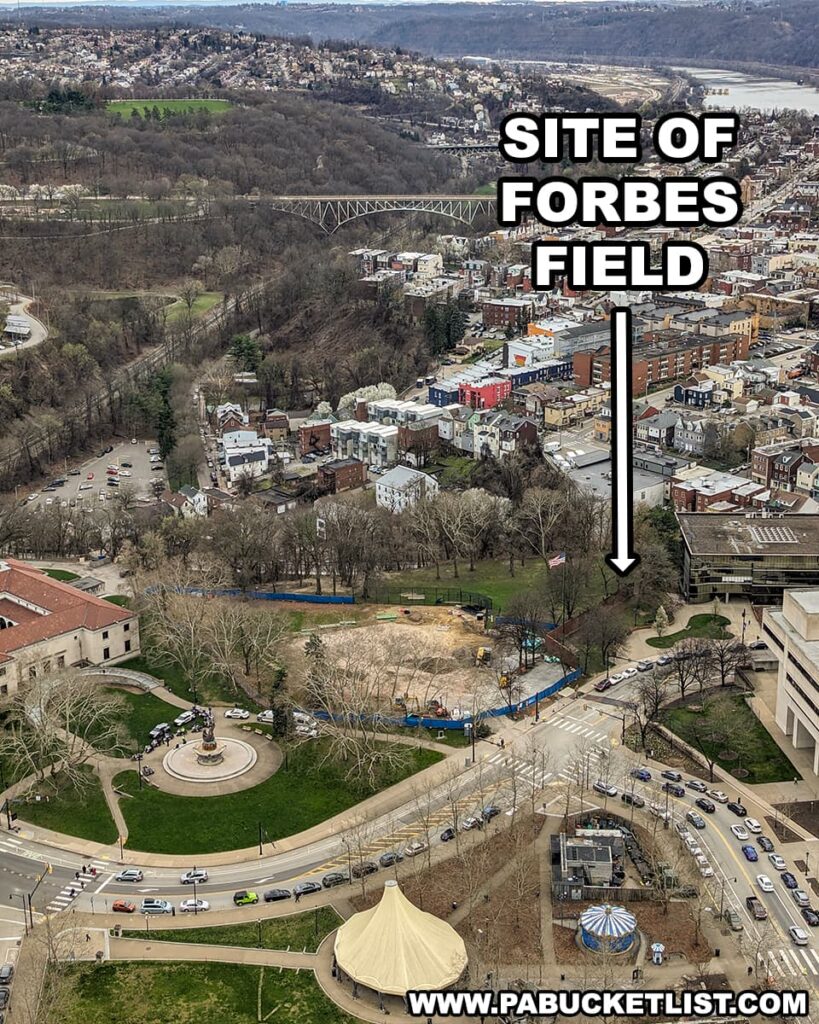 An aerial photograph points out the former site of Forbes Field in the Oakland neighborhood of Pittsburgh, with an arrow labeled "SITE OF FORBES FIELD" indicating the location. The area is now part of a modern urban landscape, with roads, vehicles, and buildings surrounding what used to be the historic ballpark. A circular plaza with a fountain sits at the forefront, and the surrounding streets bustle with city traffic. In the distance, the rolling hills and the serpentine flow of a river are visible, showing the proximity of the urban environment to the natural landscapes around Pittsburgh. This image captures the evolution of the cityscape from the days when Forbes Field was the epicenter of baseball in Pittsburgh.
