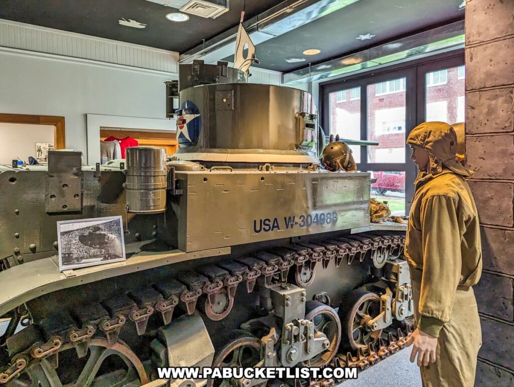 A colorful image inside the Stuart Tank Museum in Berwick, Pennsylvania, featuring an olive green M3 Stuart tank on display, with "USA W-304098" painted on its side, accompanied by a mannequin in World War II era military gear, and a historical photograph in the foreground.
