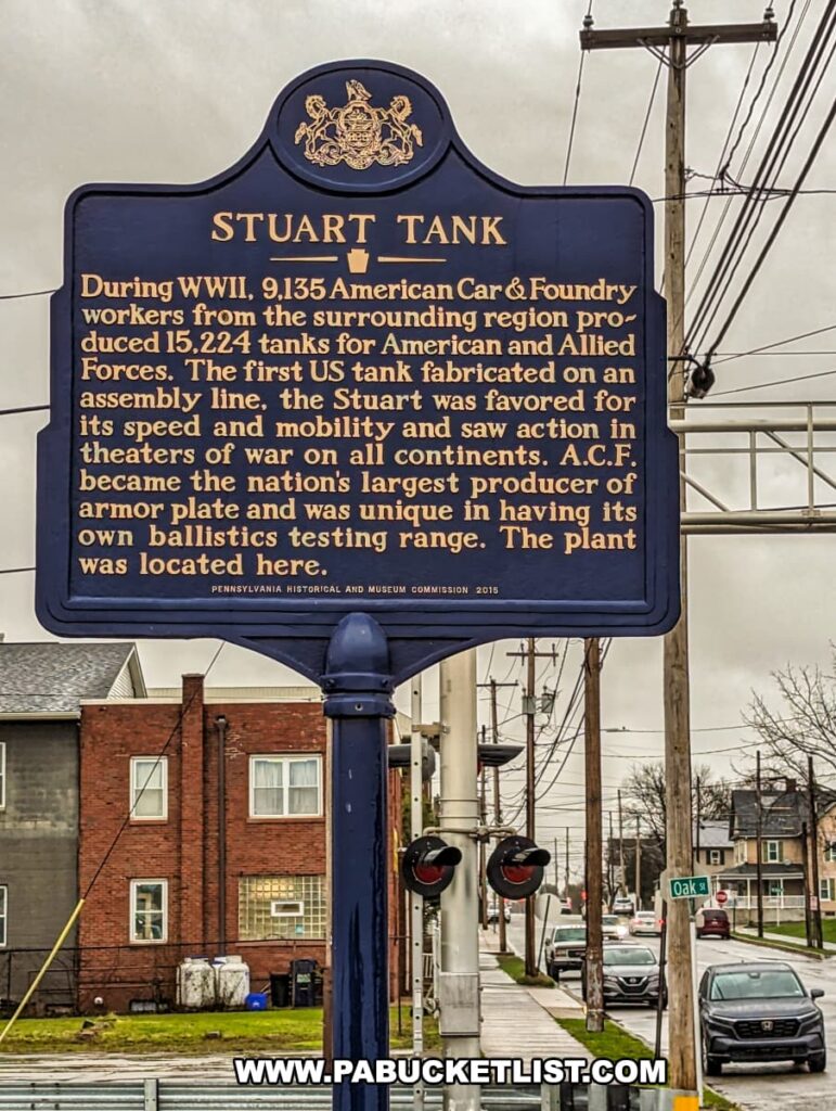 A Pennsylvania historical marker outside the Stuart Tank Museum in Berwick, detailing the WWII efforts of the American Car & Foundry workers in producing 15,224 Stuart tanks, with the background showing a residential street and overcast skies.