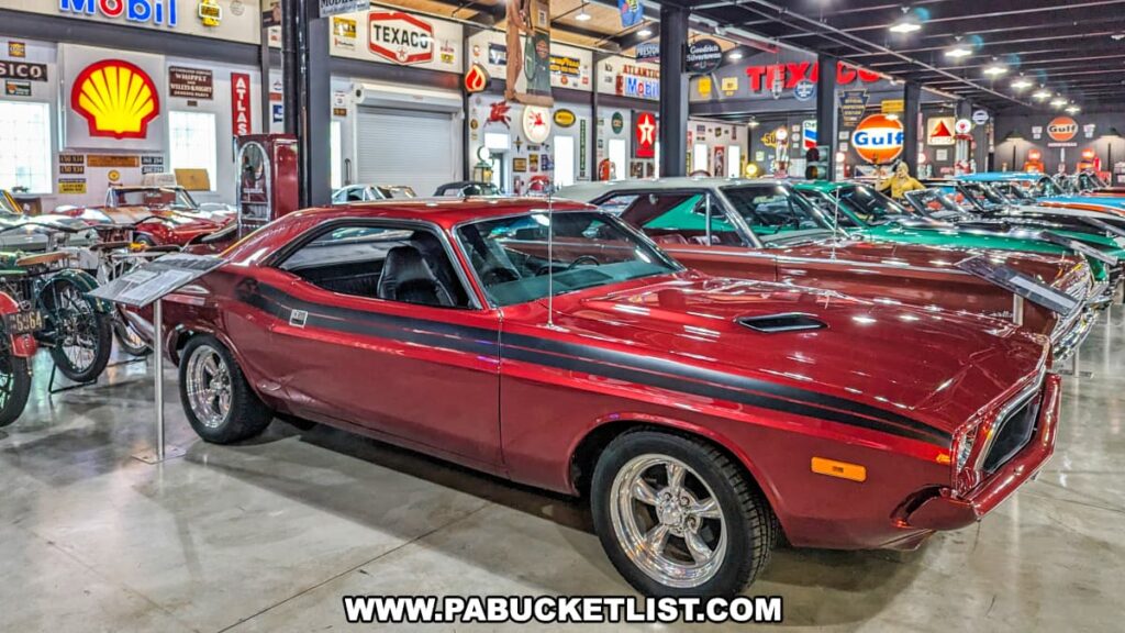 A red 1973 Dodge Challenger with black racing stripes displayed at Barry's Car Barn in Lancaster County, Pennsylvania. The classic muscle car is part of a collection featuring various vintage automobiles and motorcycles, with a backdrop of retro automotive signs and memorabilia, highlighting the museum's focus on American muscle cars from the 50s, 60s, and 70s.