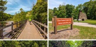 Four images from a bike ride along the Ghost Town Trail in western Pennsylvania. The first image shows a cyclist riding over a wooden bridge surrounded by lush green trees. The second image features a sign for the Eliza Furnace Historic Site, with a stone furnace and informational displays in the background. The third image captures an orange bicycle parked in front of a graffiti-covered wall that reads "Ghost Town Trail" amidst dense forest. The fourth image depicts a narrow, tree-lined trail with steep rock walls, where the same orange bicycle is parked on the path.