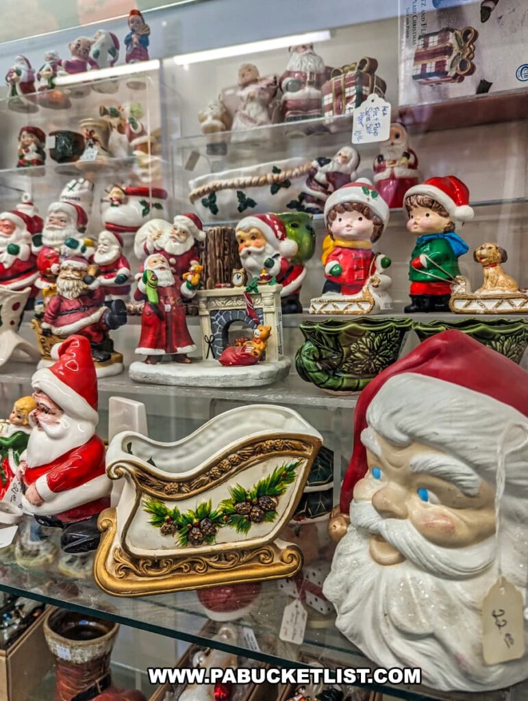 A display case at Cackleberry Farm Antique Mall in Lancaster County, PA, filled with an assortment of vintage Christmas decorations. The collection includes various Santa figurines, festive sleighs, and ceramic children in holiday attire. Each piece is meticulously arranged, showcasing the intricate details and nostalgic charm of these holiday collectibles. The bright and colorful decorations create a festive and inviting atmosphere within the antique mall.