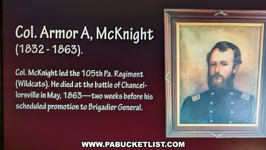 A historical display at the Jefferson County History Center in Brookville, Pennsylvania, featuring information about Col. Armor A. McKnight (1832-1863). The display includes a portrait of Col. McKnight in a wooden frame. The text explains that Col. McKnight led the 105th Pennsylvania Regiment (Wildcats) and died at the Battle of Chancellorsville in May 1863, two weeks before his scheduled promotion to Brigadier General. The background of the display is a dark red color, highlighting the portrait and the informative text.