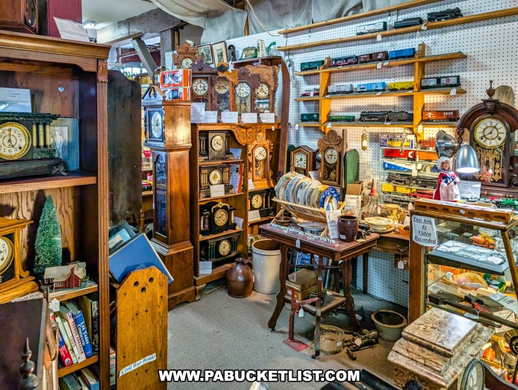 A booth inside Rollermills Antique Marketplace in Lewisburg, PA, filled with antique clocks, model trains, vintage books, decorative pottery, and various collectibles, all displayed on wooden shelves and tables within the historic 1880s flour mill setting.