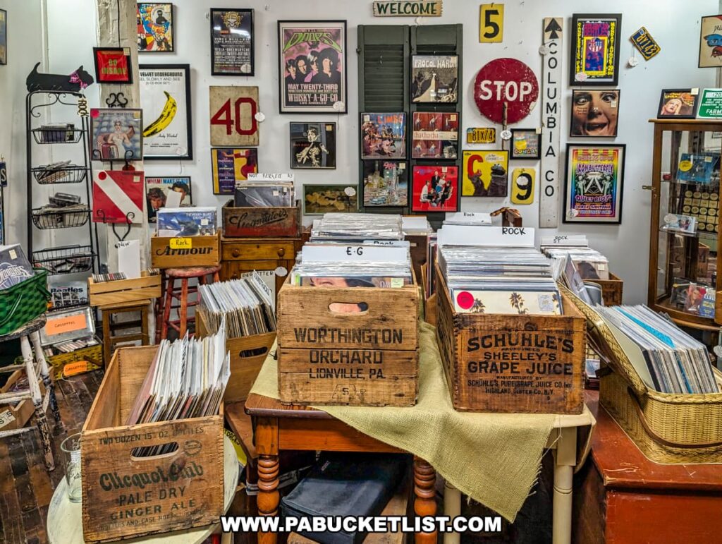 A vendor booth inside Rollermills Antique Marketplace in Lewisburg, PA, featuring an extensive collection of vintage vinyl records organized in wooden crates, with classic album covers displayed on the walls alongside retro signage, music memorabilia, and nostalgic decor, creating a vibrant space for collectors and music enthusiasts.