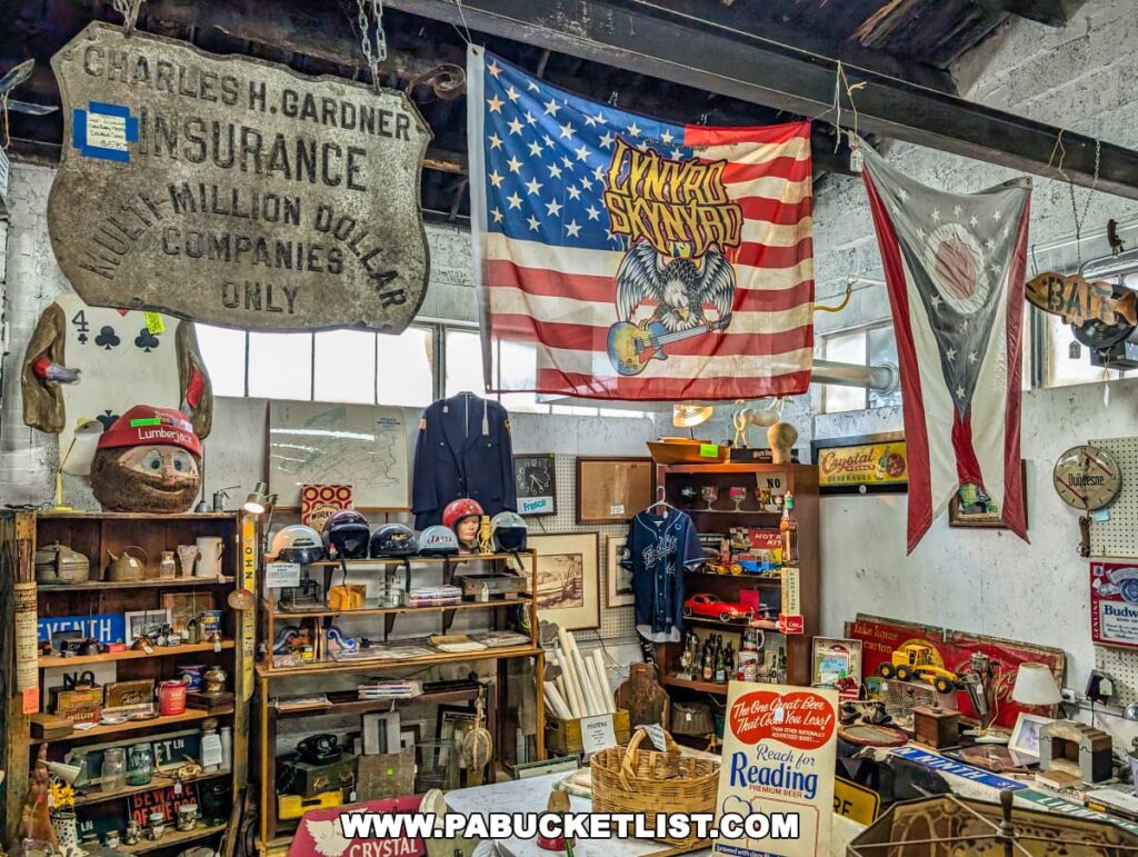 Interior of the Duncansville Antiques Co-Op in Blair County, Pennsylvania, showcasing an eclectic mix of vintage collectibles, including an old insurance sign, a Lynyrd Skynyrd flag, a historical Ohio state flag, vintage helmets, glassware, and retro advertising memorabilia arranged on shelves and walls.