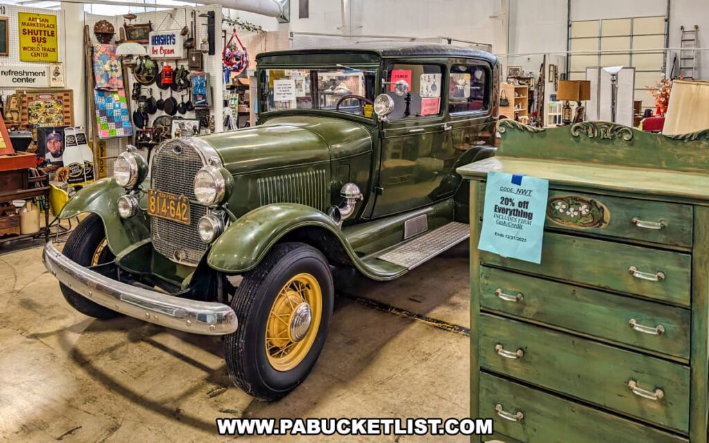 A vintage green car displayed inside the Lewisburg Antique Malls in Union County, Pennsylvania, surrounded by antique furniture, collectibles, and nostalgic décor items, creating an engaging shopping experience.