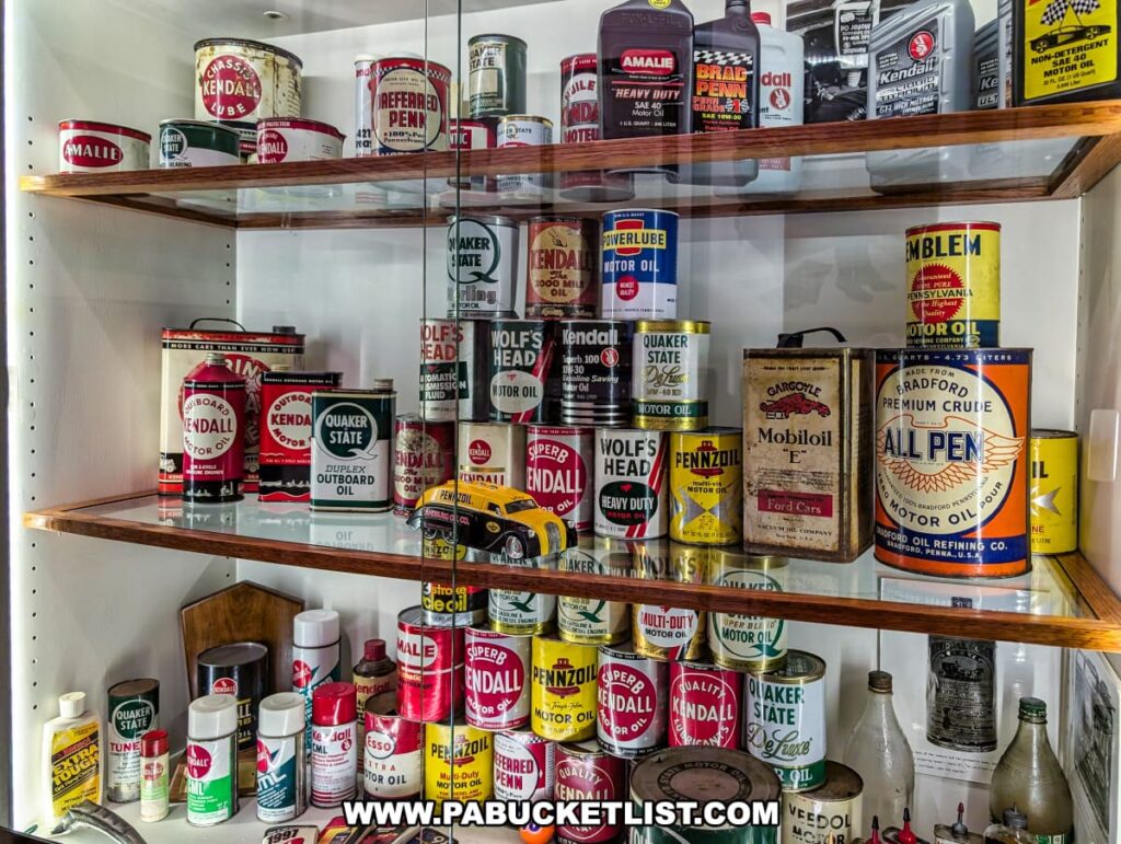 Display of vintage oil cans and containers at the Penn Brad Oil Museum in McKean County, Pennsylvania, featuring colorful packaging from well-known Pennsylvania oil brands such as Kendall, Wolf’s Head, Pennzoil, Quaker State, Amalie, and All Pen, showcasing the branding and marketing history of motor oils and lubricants produced in the Bradford Oil Field region.