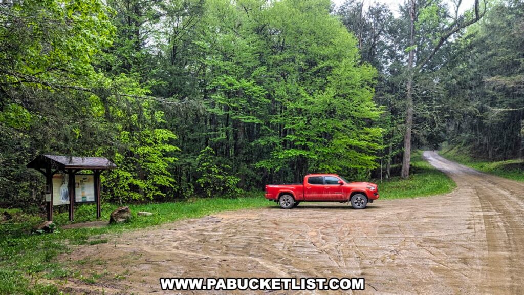 A small trailhead parking area along Brunnerdale Road in the Loyalsock State Forest near Angel Falls, featuring a red pickup truck parked beside a wooden information kiosk, with dense green forest in the background and a dirt road curving into the trees.