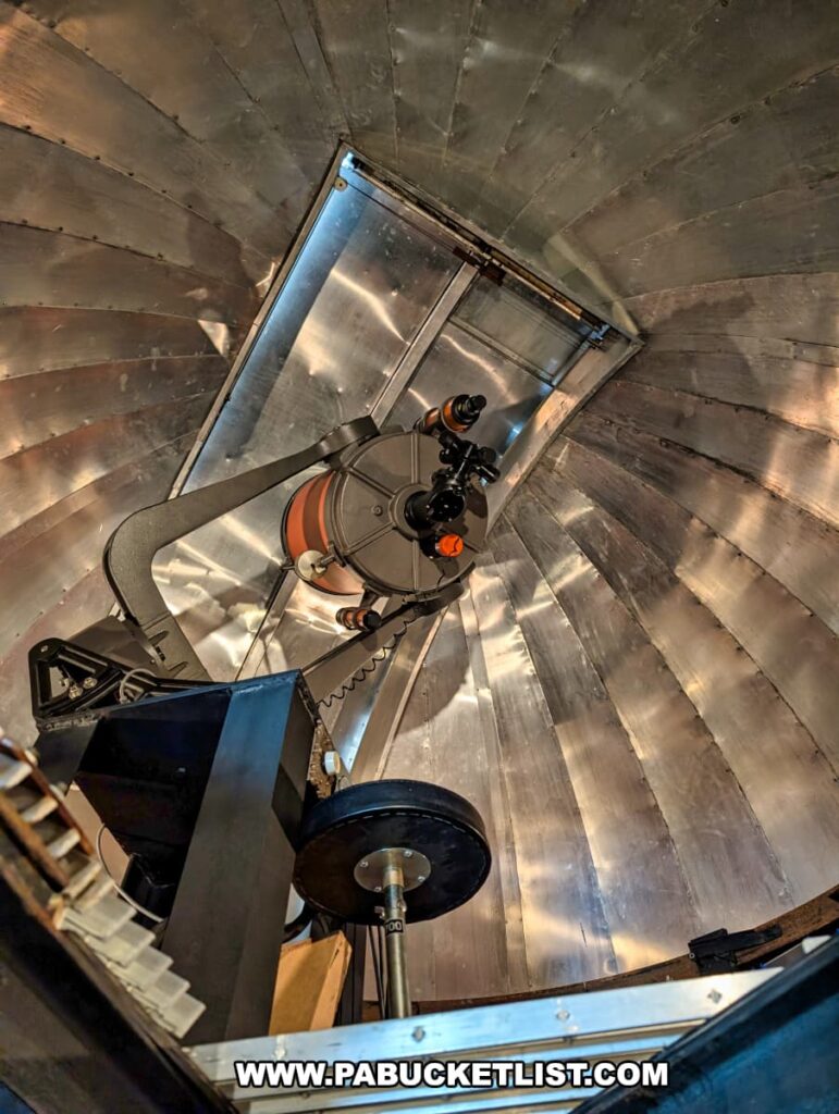 A view inside the dome of the Bayernhof Museum’s private observatory, featuring a mounted telescope aimed skyward beneath a metallic, segmented ceiling with an open hatch, highlighting yet another of the mansion’s many hidden surprises and the scientific curiosity of its creator, Charles B. Brown III.